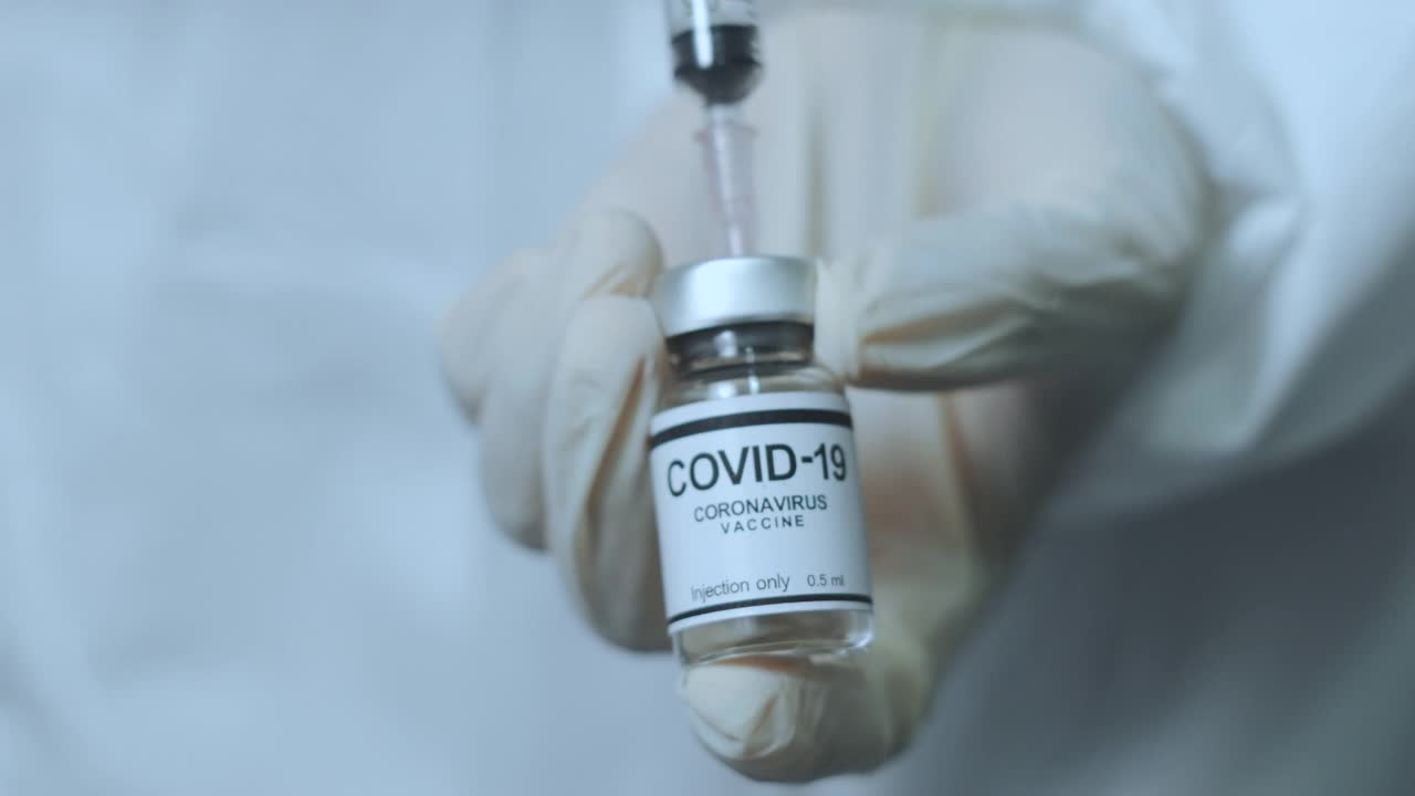 医生手持注射器和Covid-19疫苗瓶视频素材