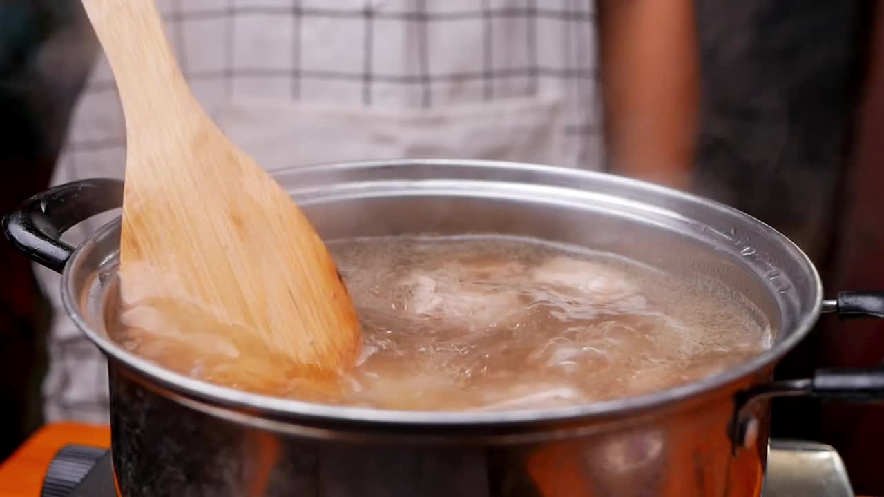 在厨房的电炉上用锅煮猪排汤。烹饪概念。视频素材