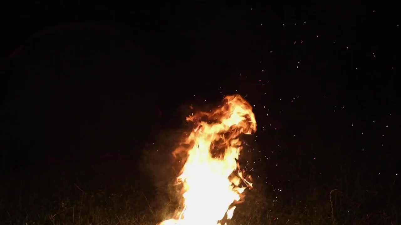 火焰，飞溅的火花和黑色背景上的烟雾。夜晚的篝火碎片，慢镜头。视频素材