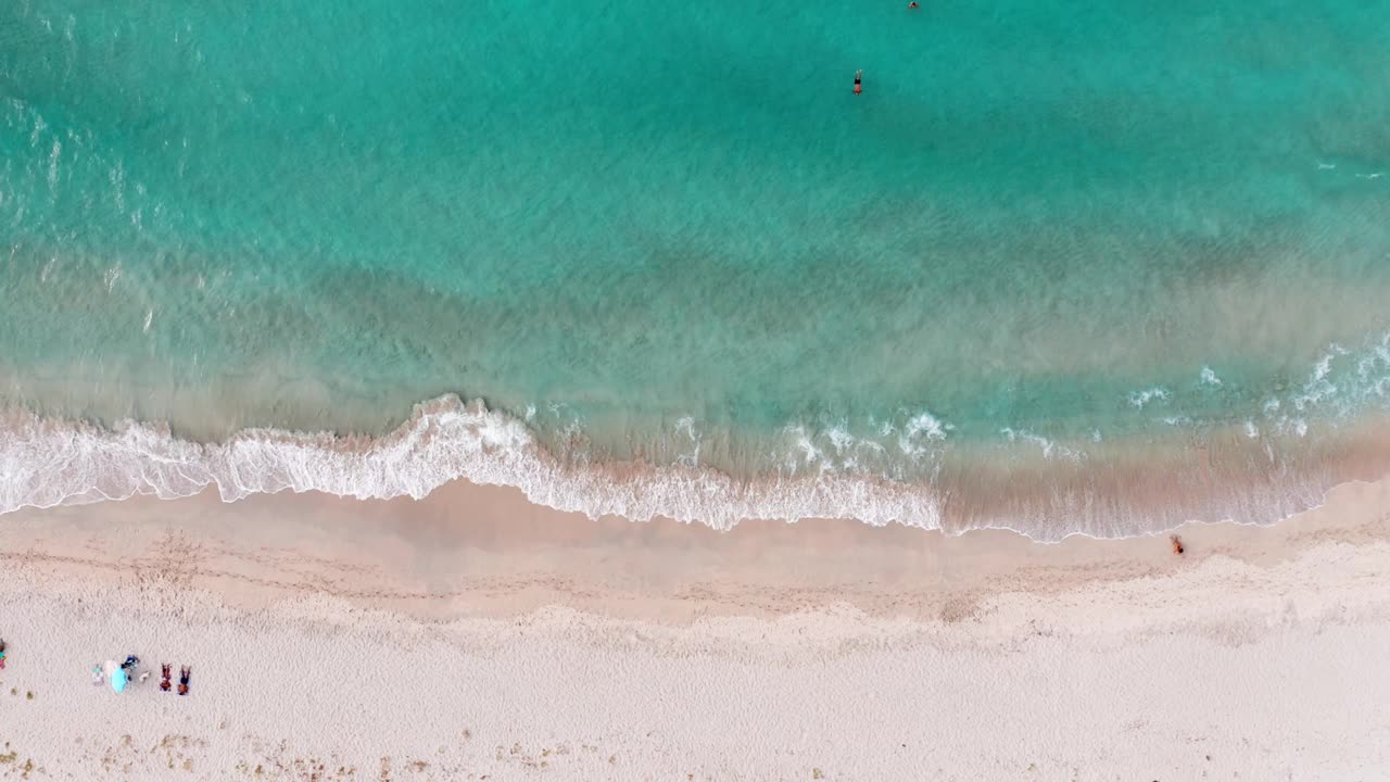 俯瞰海面上的日落。美丽的海浪。粉色的沙滩和迷人的大海。夏天的海景。人们在海滩上放松。水结构。俯视图的奇妙的自然日落。视频素材