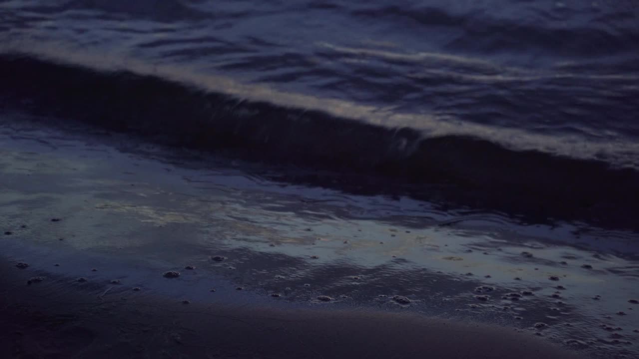 海洋或海浪撞击海滩在日落美丽的夜晚颜色。黑暗的波浪在夜晚冲刷着海岸。近距离拍摄视频素材