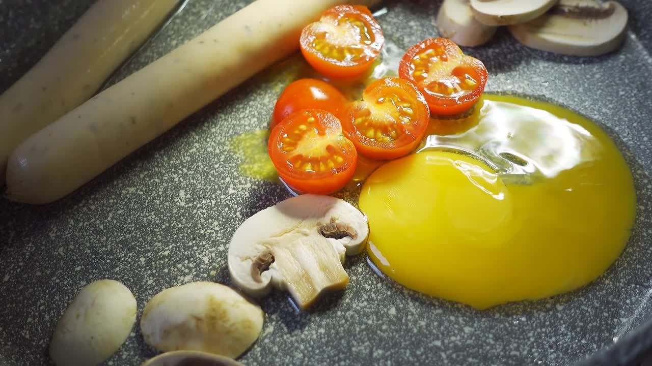 用木勺搅动着煎好的鸡蛋、蘑菇、圣女果和香肠。4 k视频,特写。视频素材