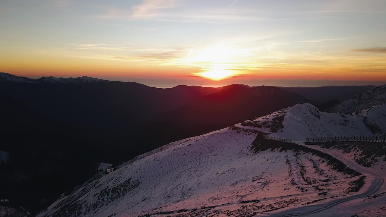 冬天山上美丽的日落。雪堆在山上，美丽的阳光照耀着视频素材