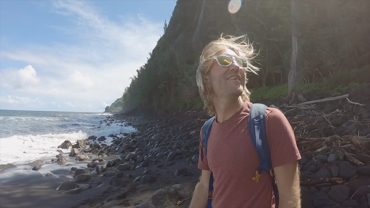 慢镜头:一名年轻人张开双臂站在充满异国情调的空旷海滩上。在海边的人举起了手臂视频素材