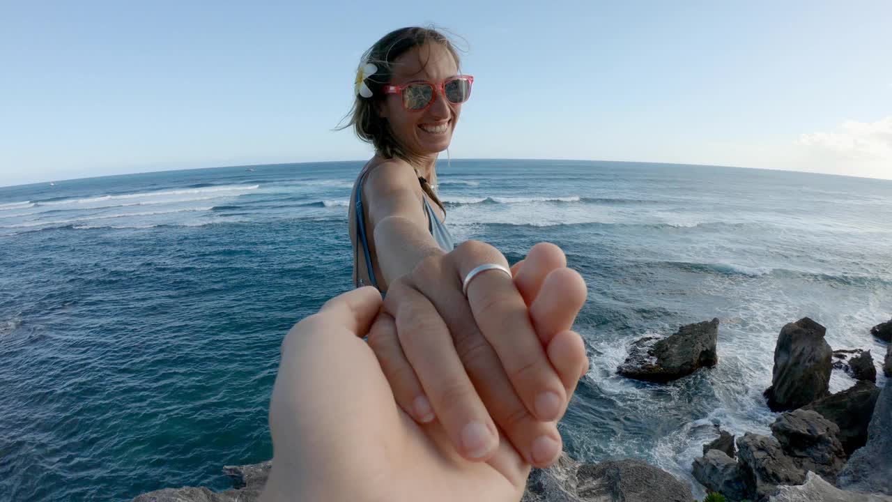 女人牵着同伴的手，带着他来到俯瞰大海的悬崖顶上。跟我到视频素材