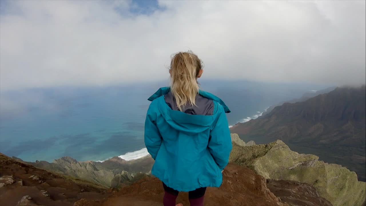 凝视自然的女人举起手臂，女性徒步旅行者在山顶俯瞰太平洋。视频素材