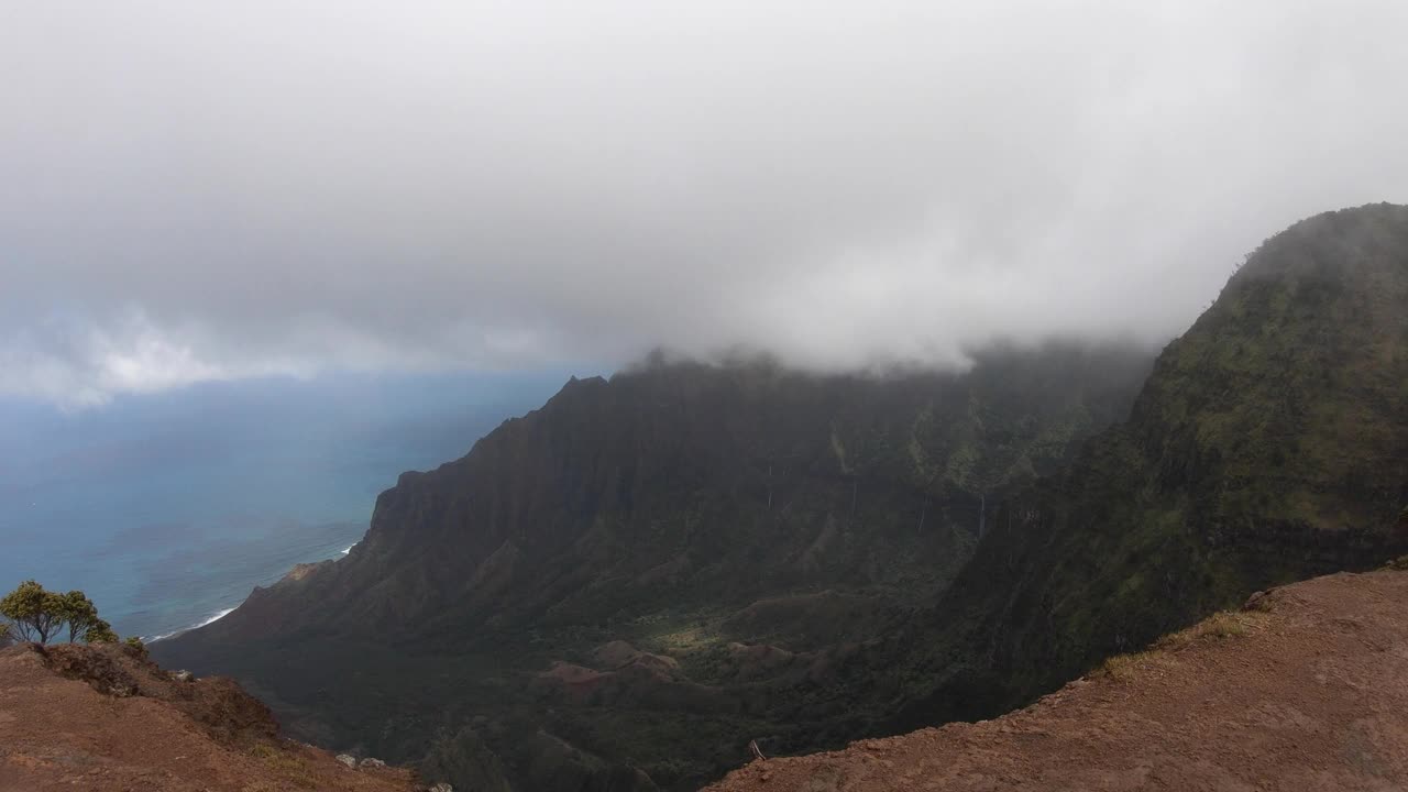 在夏威夷的纳帕利海岸，考艾岛，俯瞰太平洋的郁郁葱葱的绿色山脉上，云层快速移动视频素材