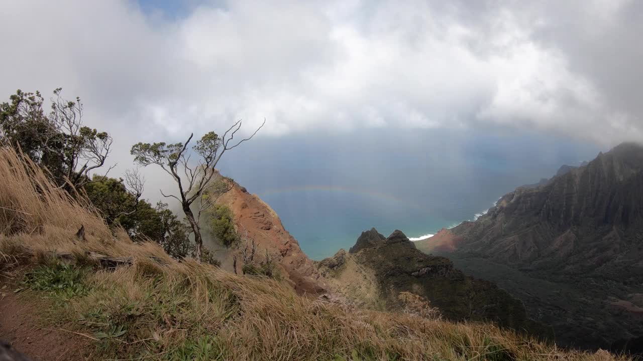 在夏威夷的纳帕利海岸，考艾岛，俯瞰太平洋的郁郁葱葱的绿色山脉上，云层快速移动视频素材