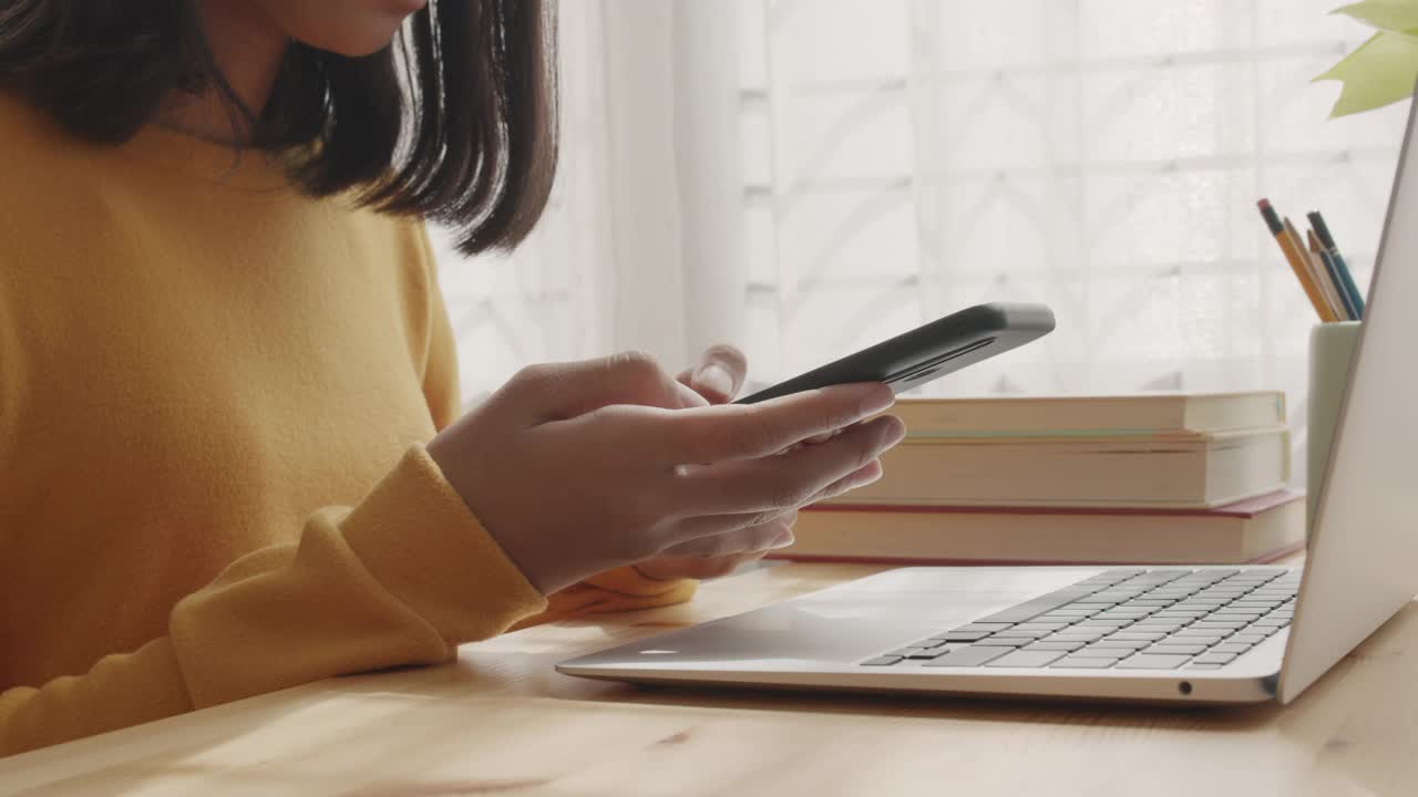 侧视图。亚洲女孩的手在家里使用电话视频素材