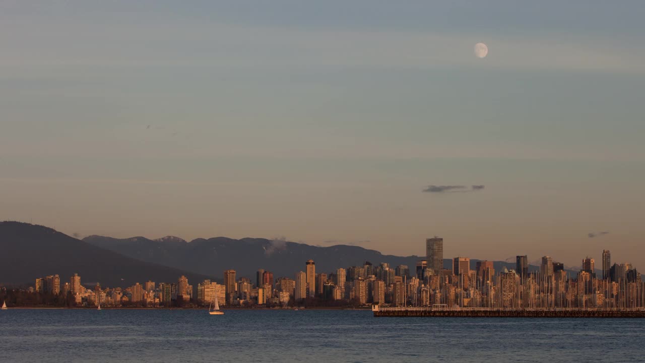 在日落到夜晚的时候，在海边对着山的城市的高层住宅建筑的延时拍摄-温哥华，加拿大视频素材