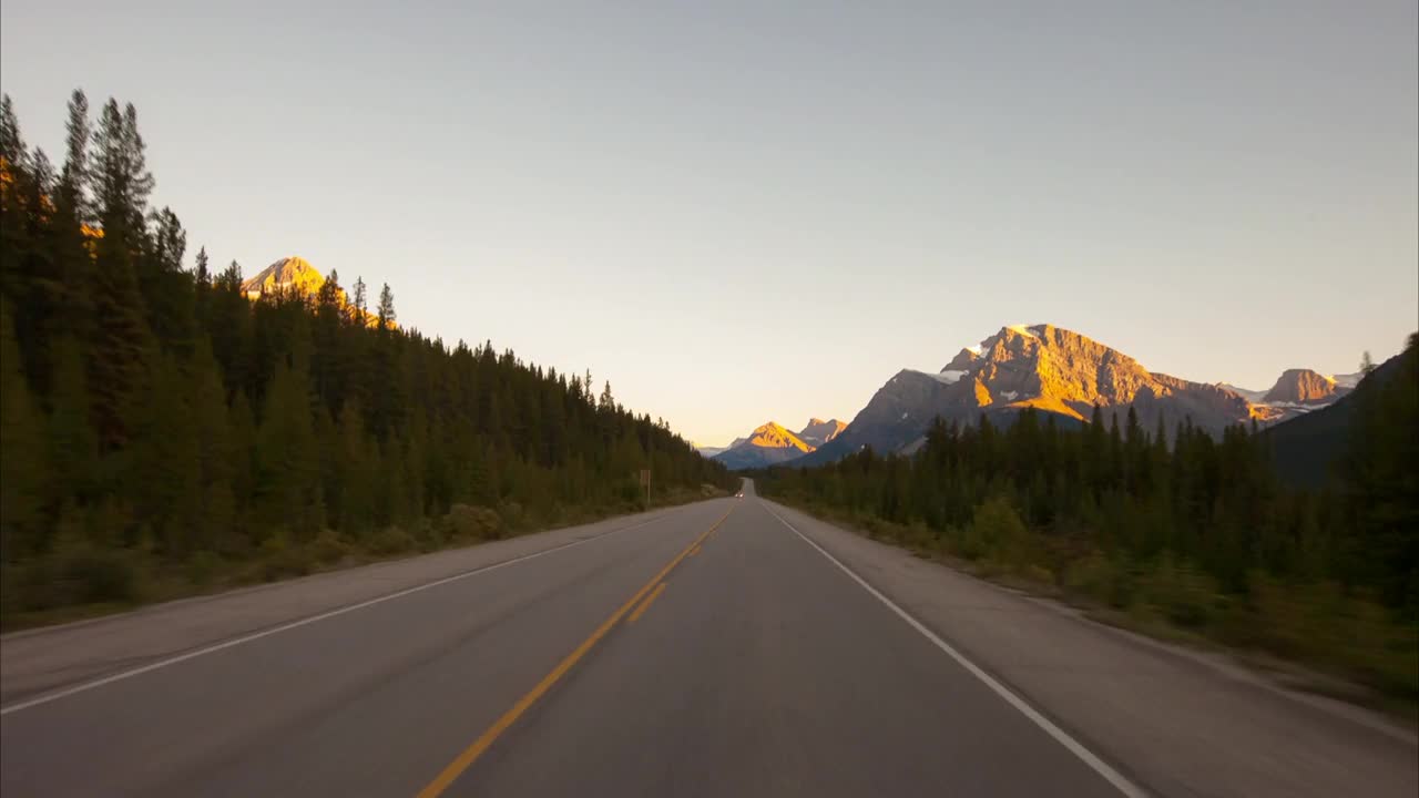 时间流逝拍摄的车辆在道路上移动在森林中对晴朗的天空在冬天-不列颠哥伦比亚省，加拿大视频素材