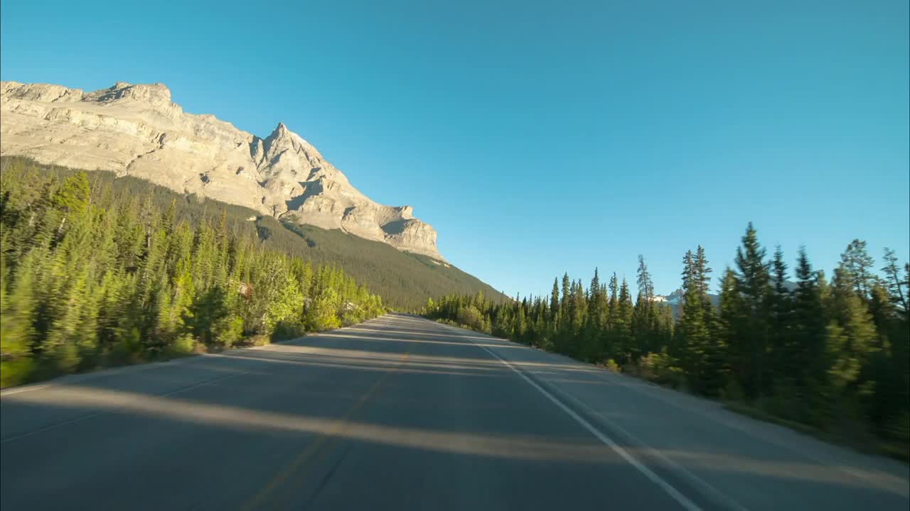 时间流逝风景雪山对晴朗的天空，道路中绿树在森林-不列颠哥伦比亚，加拿大视频素材