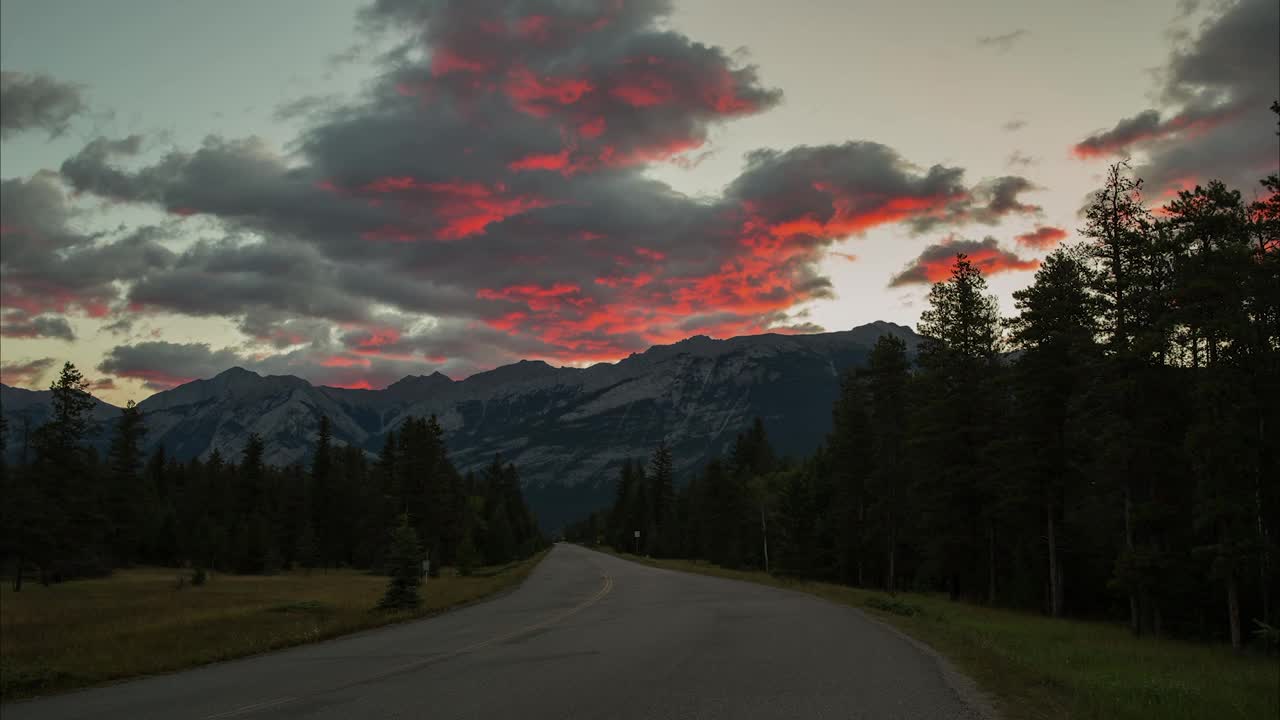 时间流逝的风景拍摄的森林中空的道路，橙色的云移动的山脉在冬天-贾斯珀，加拿大视频素材