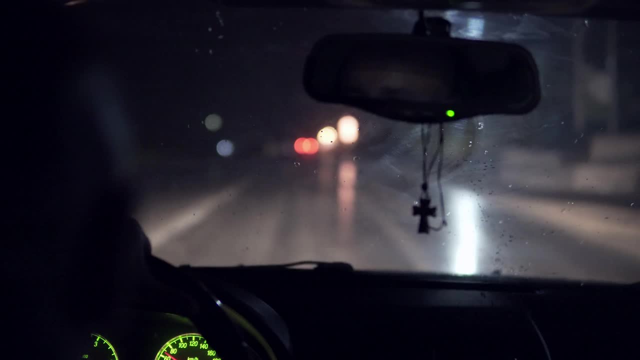 在雨夜的高速公路上，有十字镜的神父开车行驶视频素材