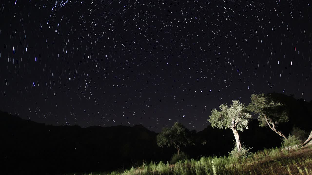 夜空中移动的恒星轨迹的时间间隔。在前景中有一座山顶的银河系的星星。夜晚天空自然夏季景观。英仙座流星雨观测。视频素材