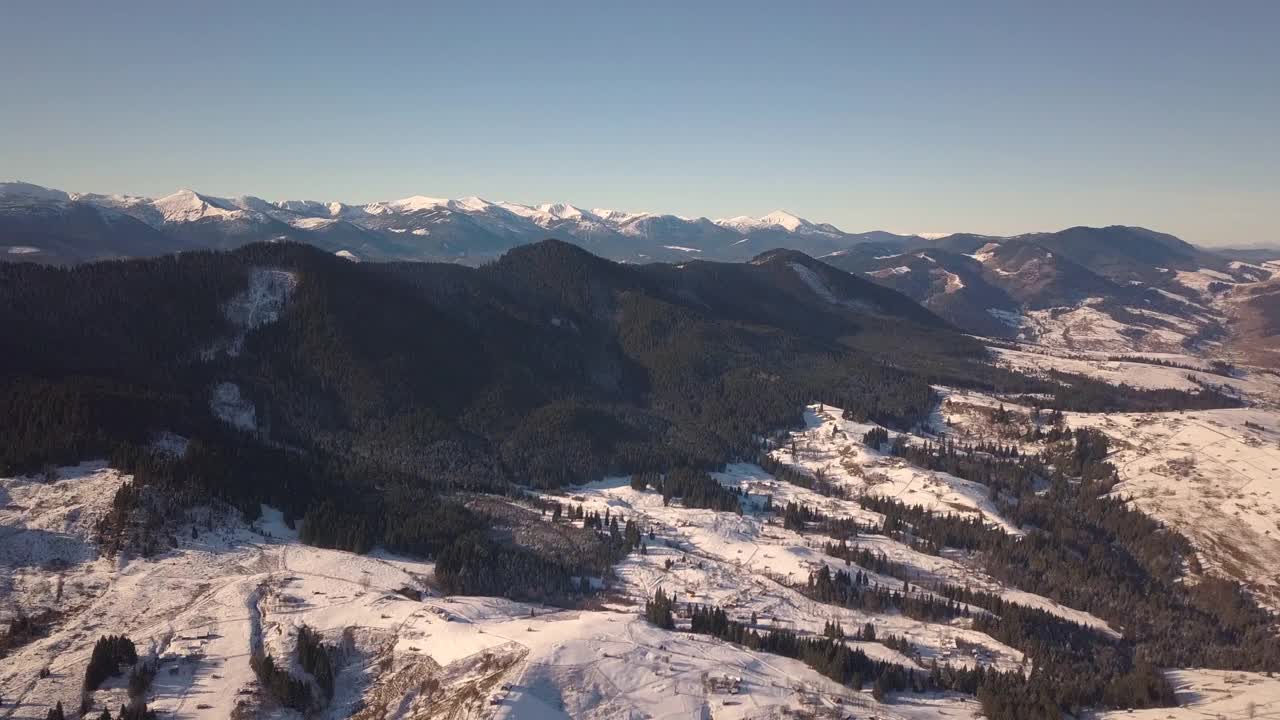 鸟瞰图上的小村庄，在冬天被雪覆盖的山丘上散落着房屋，裸露的喀尔巴阡山脉在乌克兰。视频素材