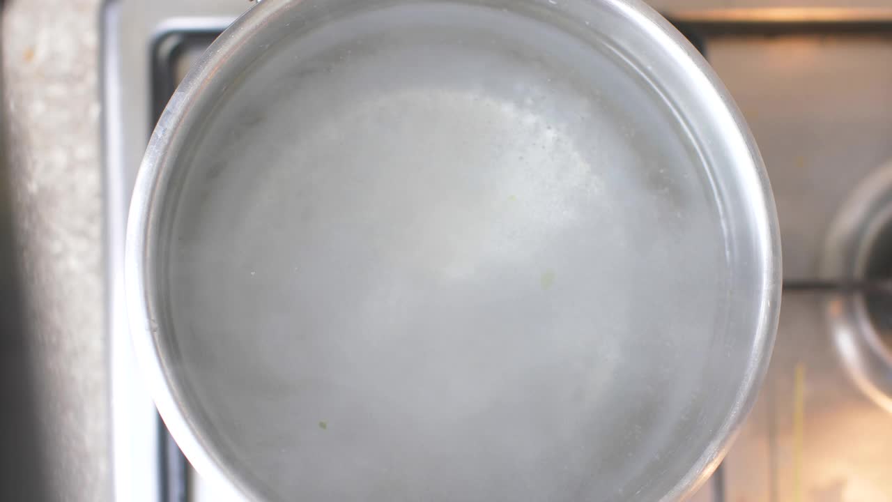 俯视图上的银锅的沸水在厨房炉子上。厨师添加正宗的意大利细面条视频下载