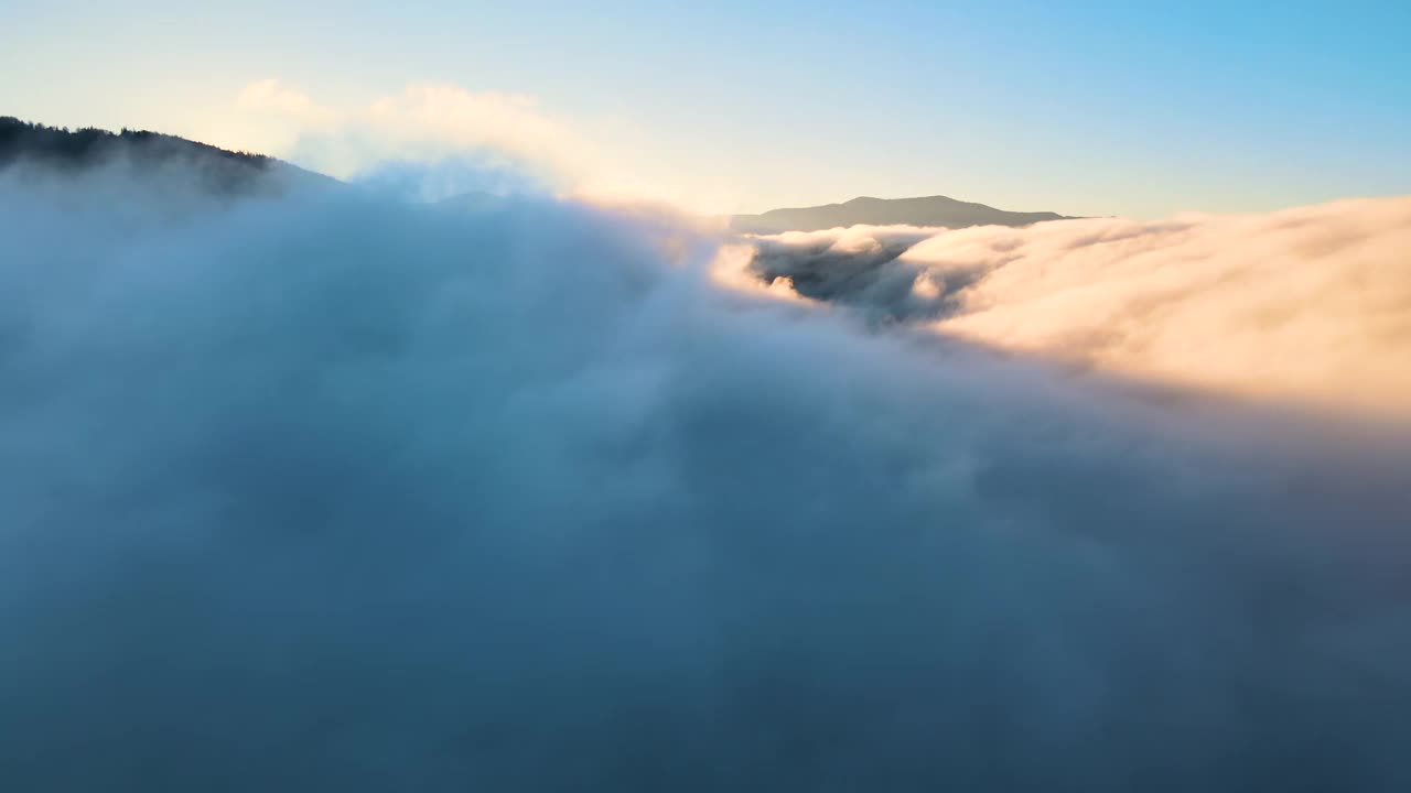 鸟瞰图的景观上方雾快速移动的云覆盖山在日落。视频素材