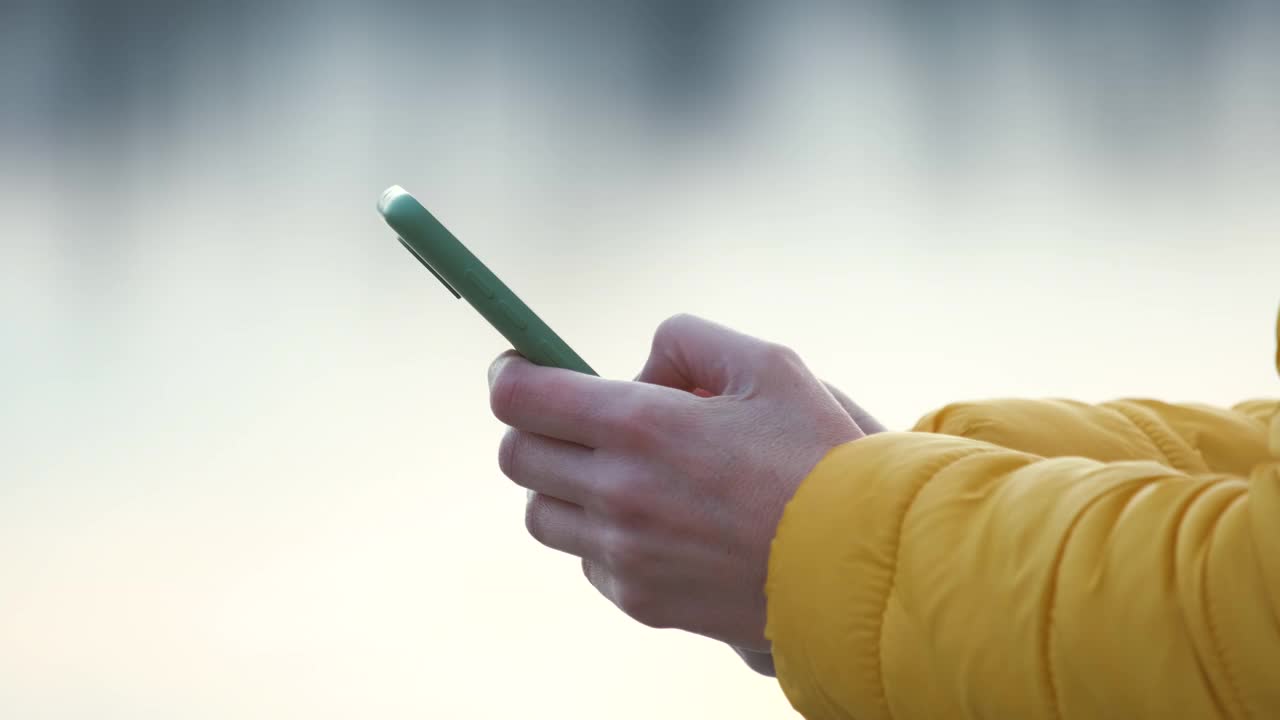 女性手握手机在城市街道上浏览互联网的特写。视频素材