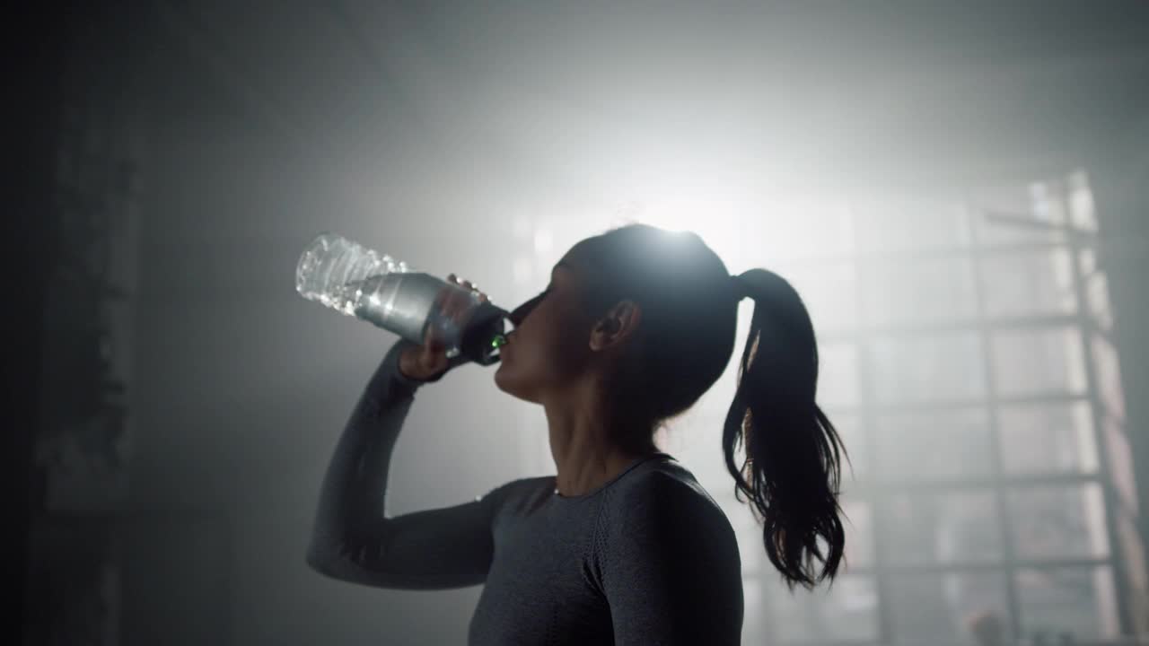 女人喝着运动瓶里的水。健身者补充水分平衡视频素材