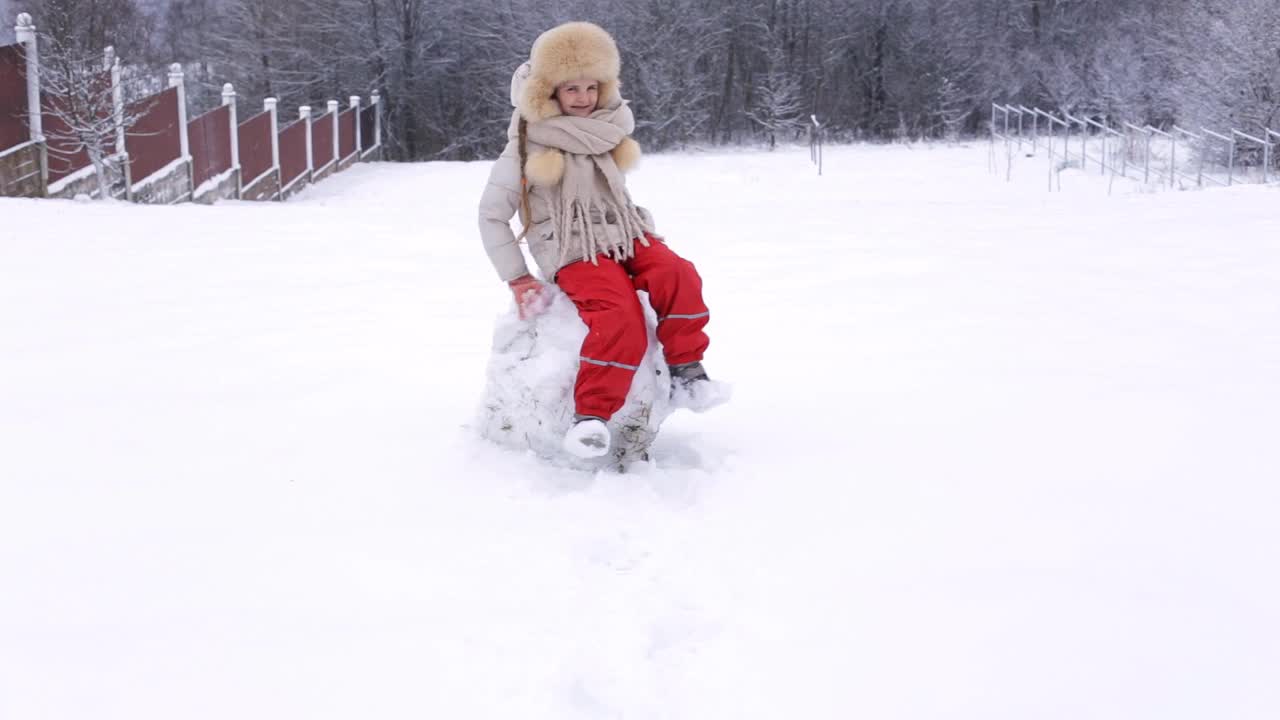 一个欧洲小孩在雪中玩耍。下雪的冬天视频素材