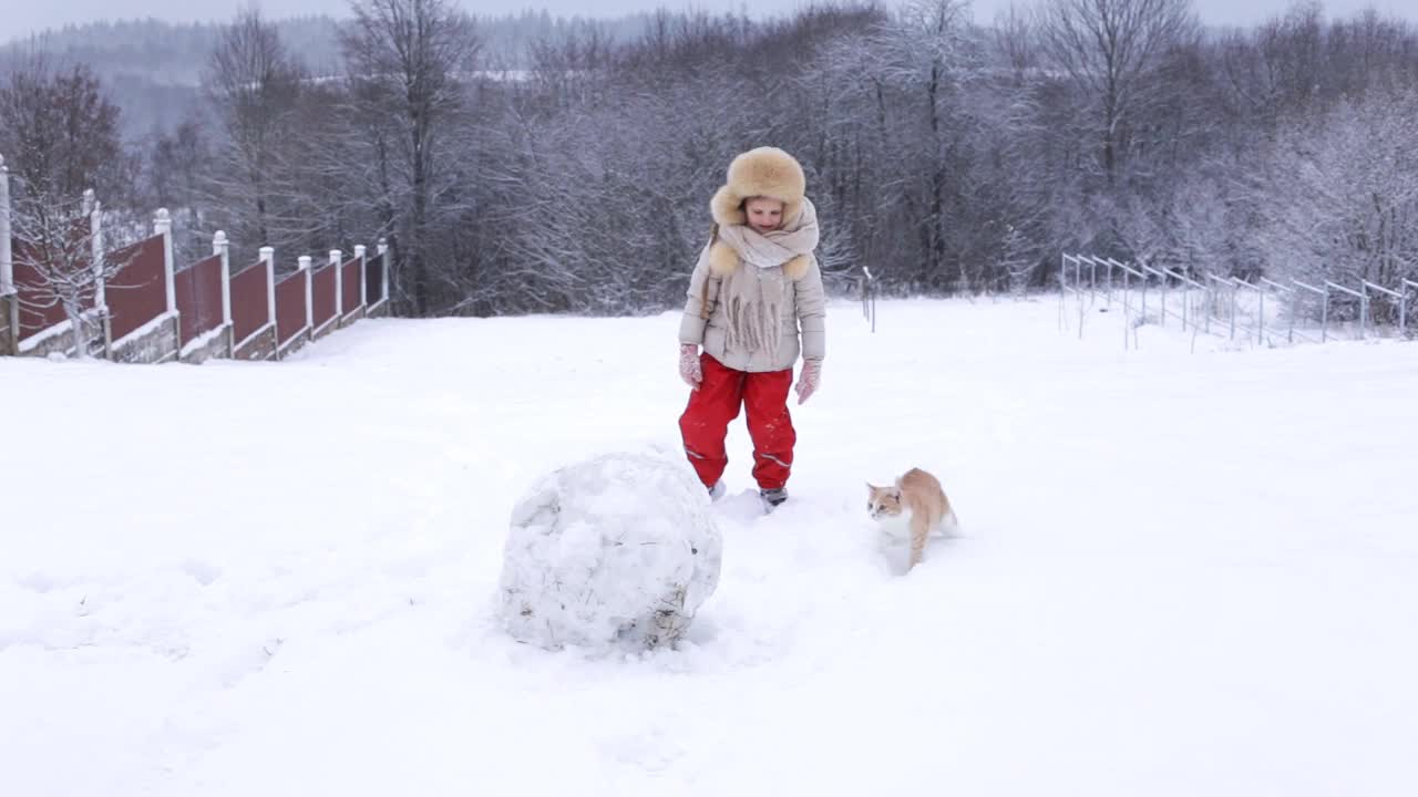 一个欧洲女孩和她的猫在下雪的天气里玩。视频下载