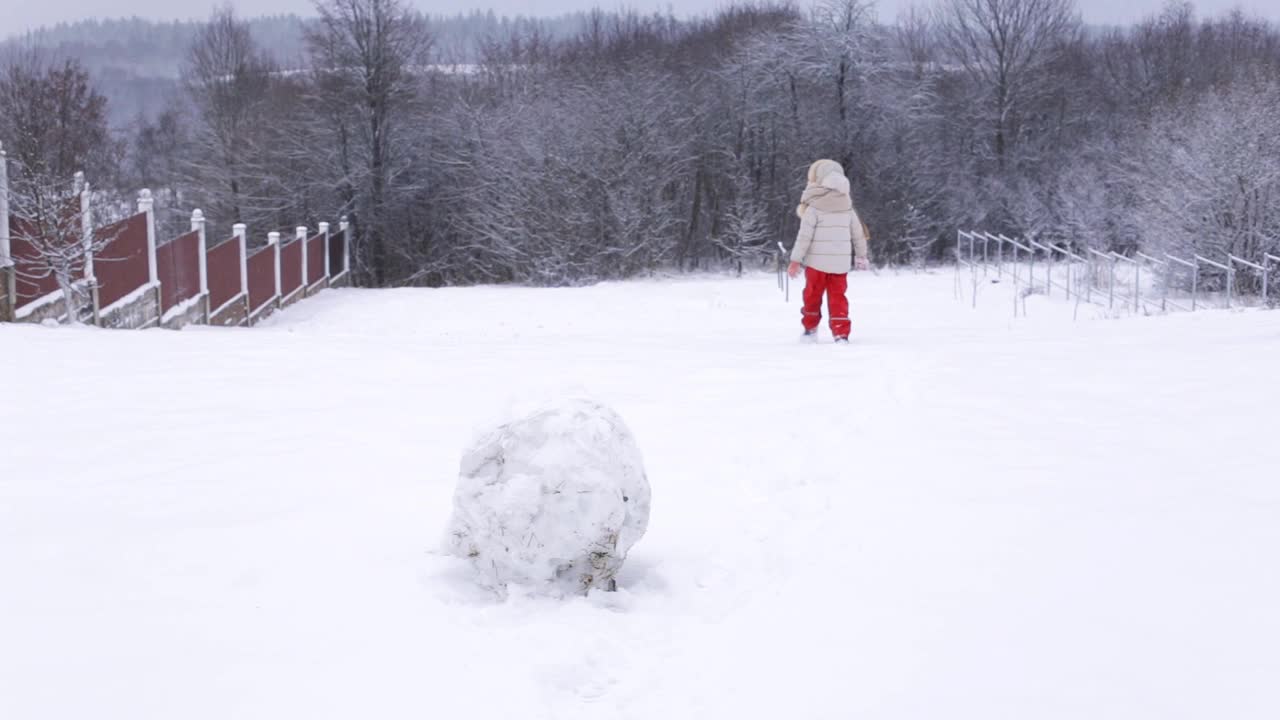 小女孩在雪山上奔跑。在冬天玩。视频素材