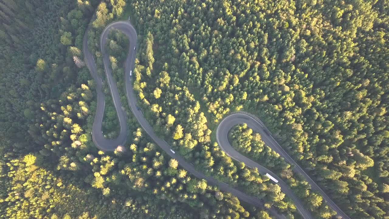 鸟瞰图蜿蜒的道路与割草汽车和卡车在高山口槽密林。视频素材