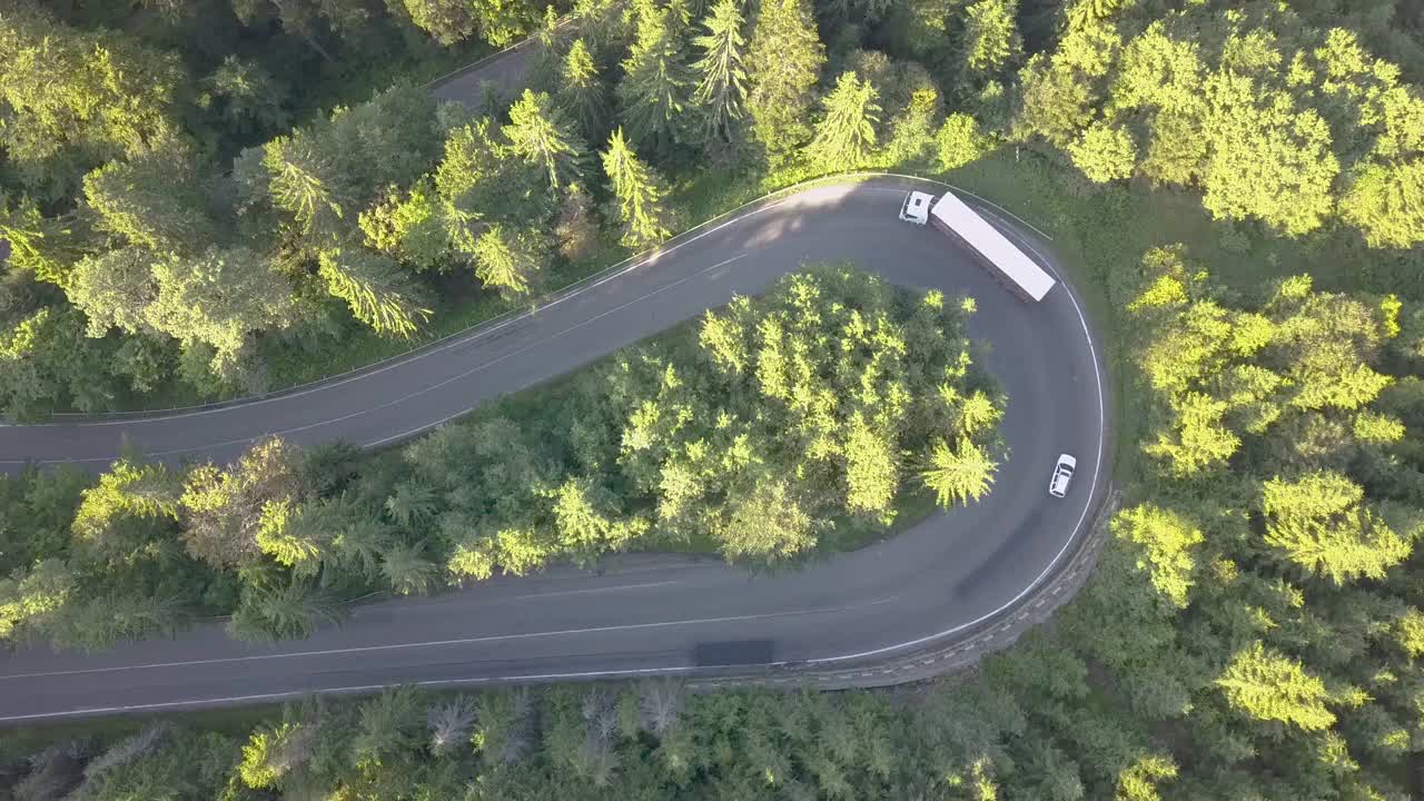 鸟瞰图蜿蜒的道路与割草汽车和卡车在高山口槽密林。视频素材