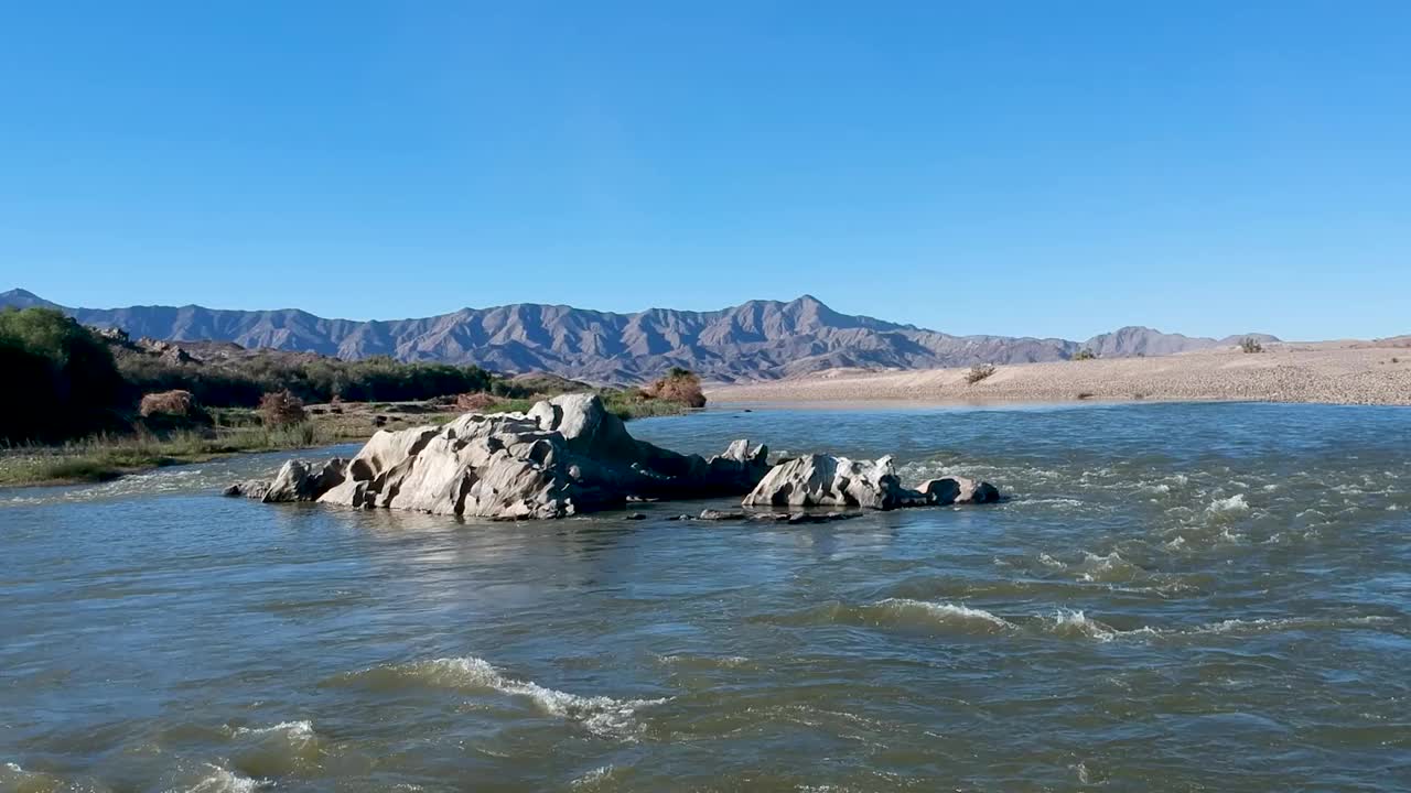 沿着湍急的河流向上移动，经过河中央的一块灰色岩石视频素材