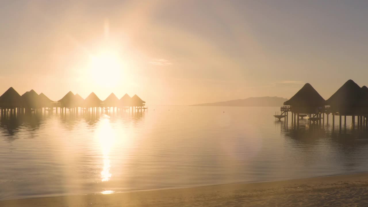 旅游度假天堂日落海滩与水上平房度假酒店在珊瑚礁泻湖海。来自波拉波拉，法属波利尼西亚，塔希提岛，南太平洋的4K视频。视频素材