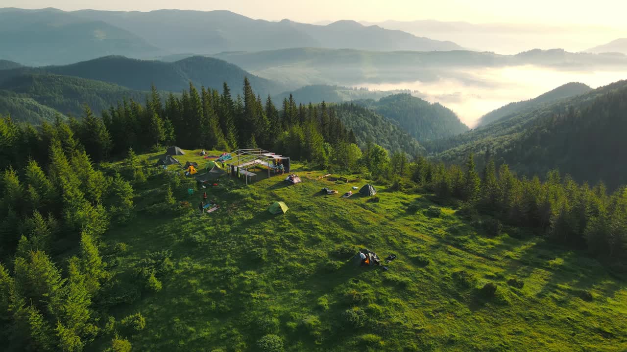 日出时，空中飞过高山中的一个帐篷营地。日出时地壳顶部的壮观景色以及山上的雾气视频素材