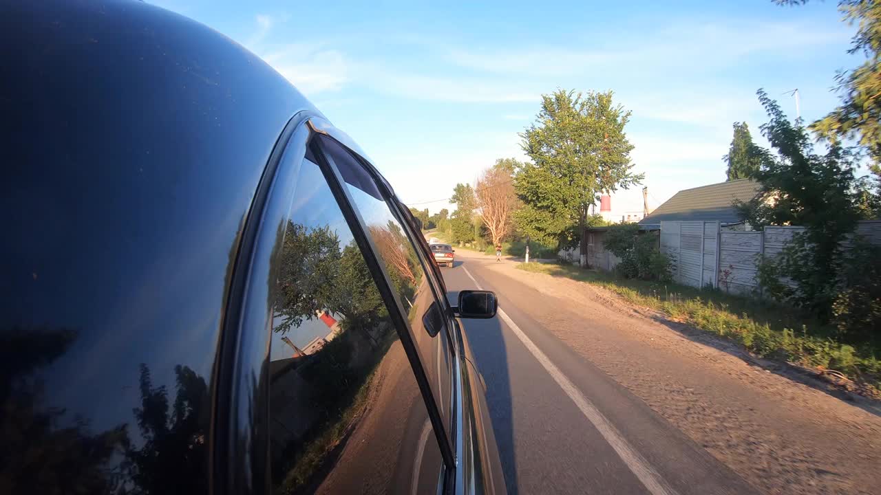 POV从旁边的汽车驶过风景优美的风景。在阳光明媚的夏日，一辆黑色轿车在马路上行驶。在乡村公路上开车。自驾游的概念。慢动作视频素材