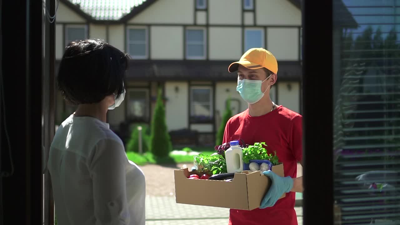 男人快递员送一盒食物给女人Spbd。志愿者捐赠新鲜蔬菜视频素材