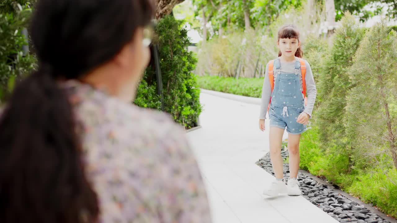 家长和小学生是携手并进的。背着背包的女人和小孩。课的开始。第一天上学。母亲送女儿上学视频素材