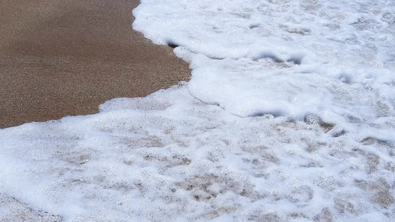 近距离观看非常平静的海浪粉碎或溅水。抽象背景，海水纹理。高清视频视频下载