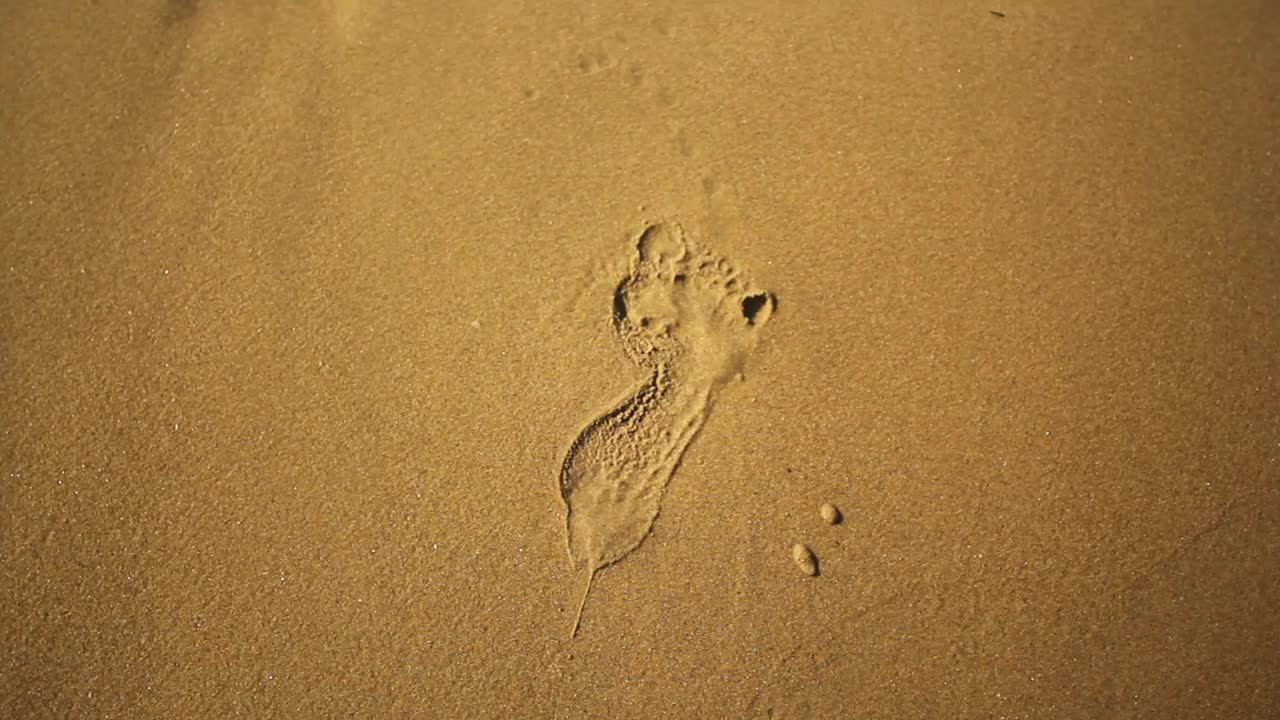 海浪冲刷着夏日海滩上的足迹视频素材