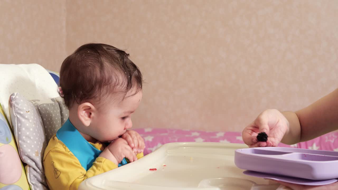 妈妈用勺子和手喂男孩，家庭食物和为人父母的观念。首先是补充食物和自我喂养视频素材