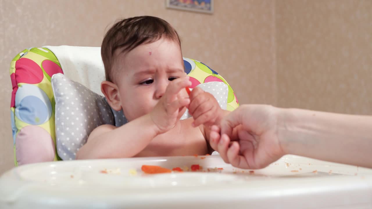 妈妈用勺子和手喂男孩，家庭食物和为人父母的观念。首先是补充食物和自我喂养视频素材