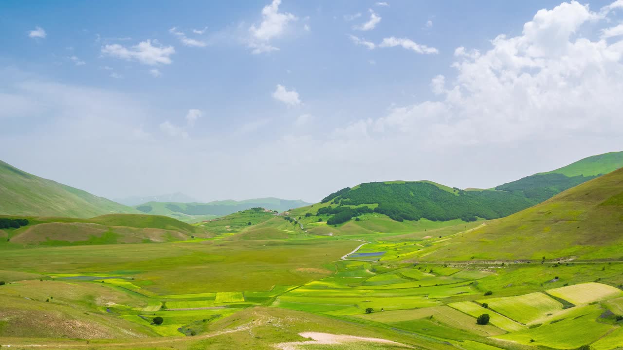 时间流逝:云层在意大利诺尔恰高地上移动。村庄坐落在山顶上，上面是盛开的农田，这是亚平宁地区著名的五颜六色的开花平原视频素材