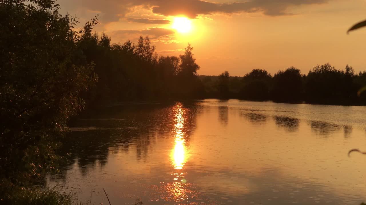 湖面上的夕阳与水面上的太阳和地平线上森林的剪影视频素材