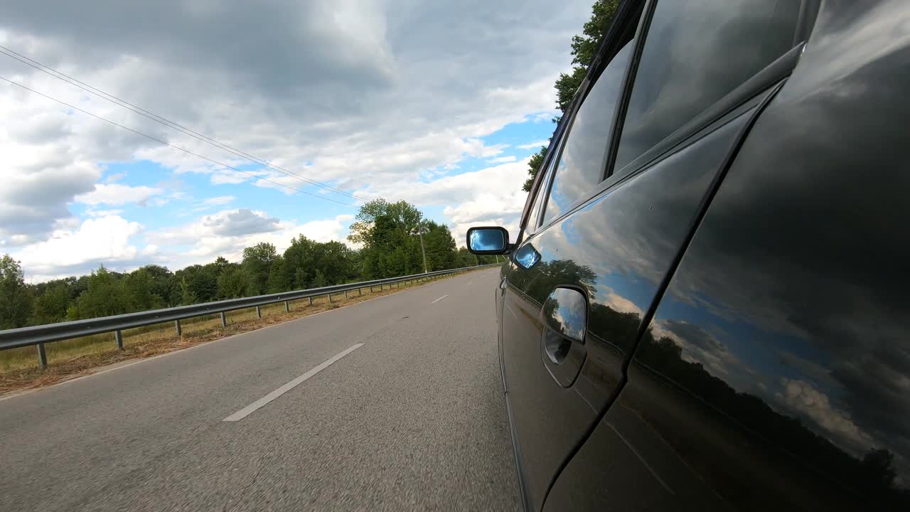 汽车穿越美丽的风景。乡村公路上自动驾驶的POV。夏天的一天，一辆黑色轿车在马路上行驶。公路旅行的概念。慢动作视频素材