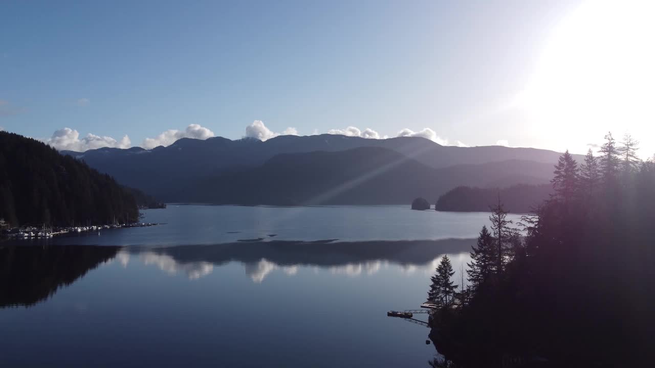 在阳光明媚的早晨飞过不列颠哥伦比亚省海湾清澈平静的水面视频素材