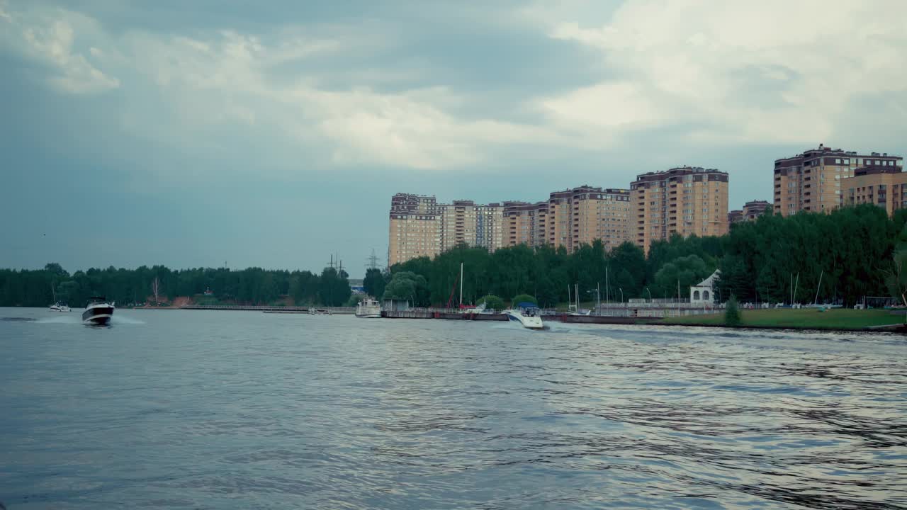 一艘游艇在一个阴天驶过海湾。城市是背景视频素材