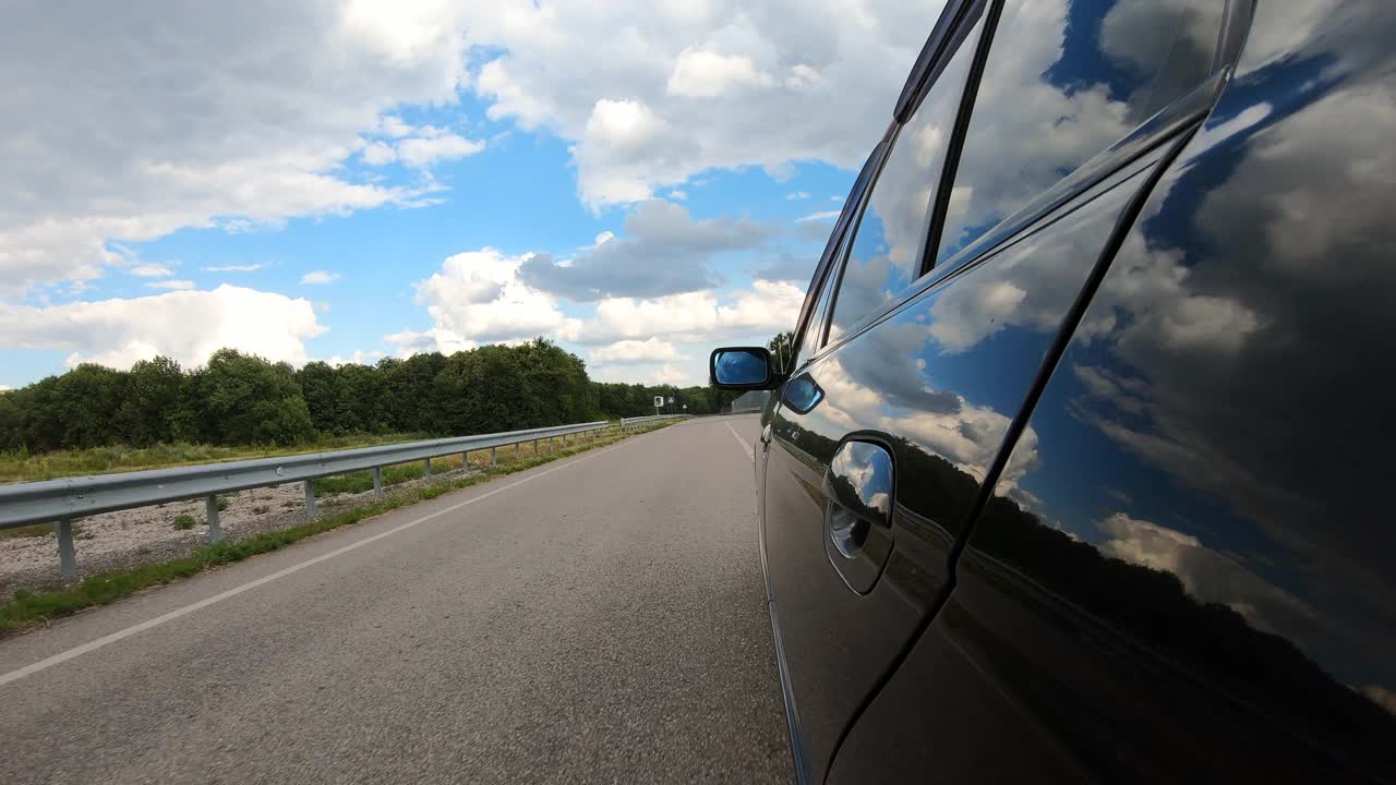 汽车穿越美丽的风景。乡村公路上自动驾驶的POV。夏天的一天，一辆黑色轿车在马路上行驶。公路旅行的概念。慢动作视频素材