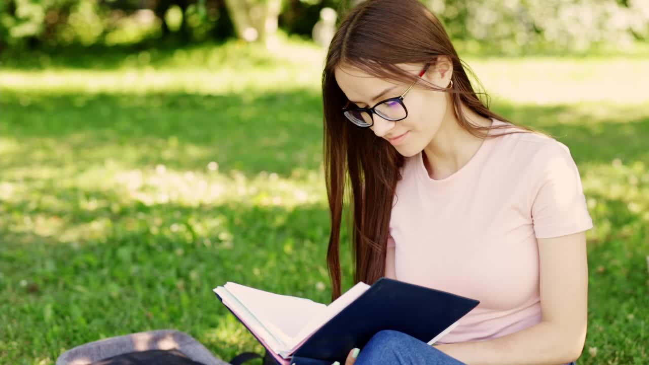 少年正坐在草地上学习，一个女学生在大学公园的一棵树下拿着书包和课本视频素材