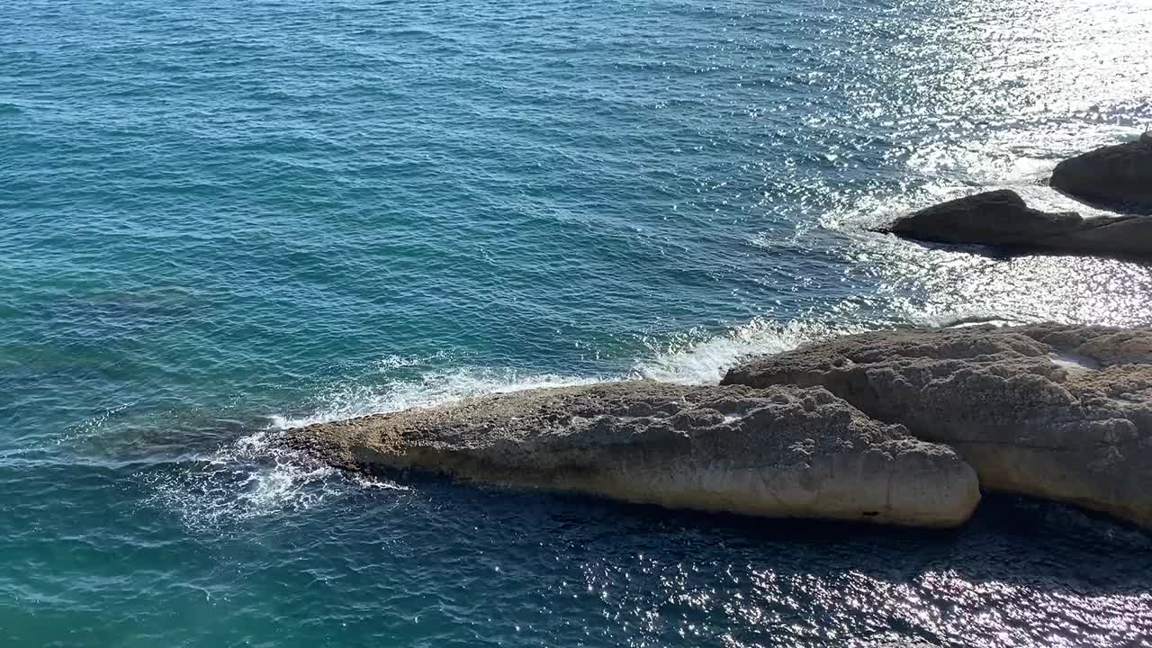 海浪拍打着海岸的岩石。蓝绿色的海水彩。美丽闪亮的地中海海岸海景。视频素材