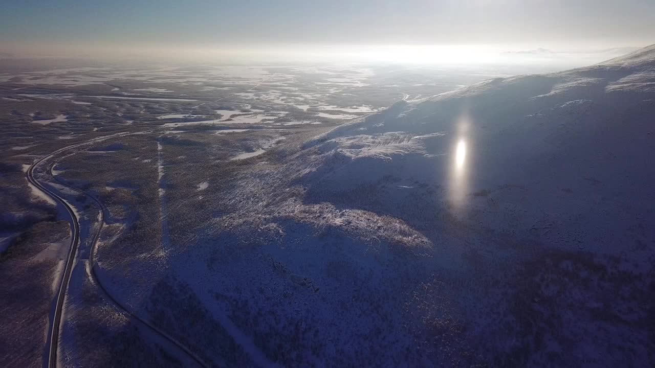 空中阳光明媚的冬季阿比斯科国家公园，基卢纳市，拉普兰，诺博顿县，瑞典，从无人机拍摄，与道路和山脉视频素材