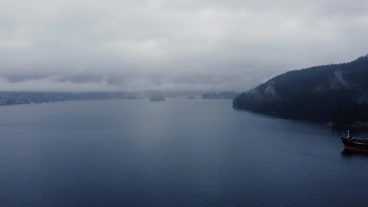 在雨中飞过海湾，尾随油轮拖曳视频素材