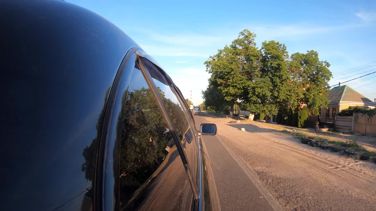 阳光明媚的夏日，黑色汽车沿着公路行驶。POV从车的侧面驶过美丽的风景。在乡间道路上行驶的汽车。自驾游的概念。慢动作视频素材